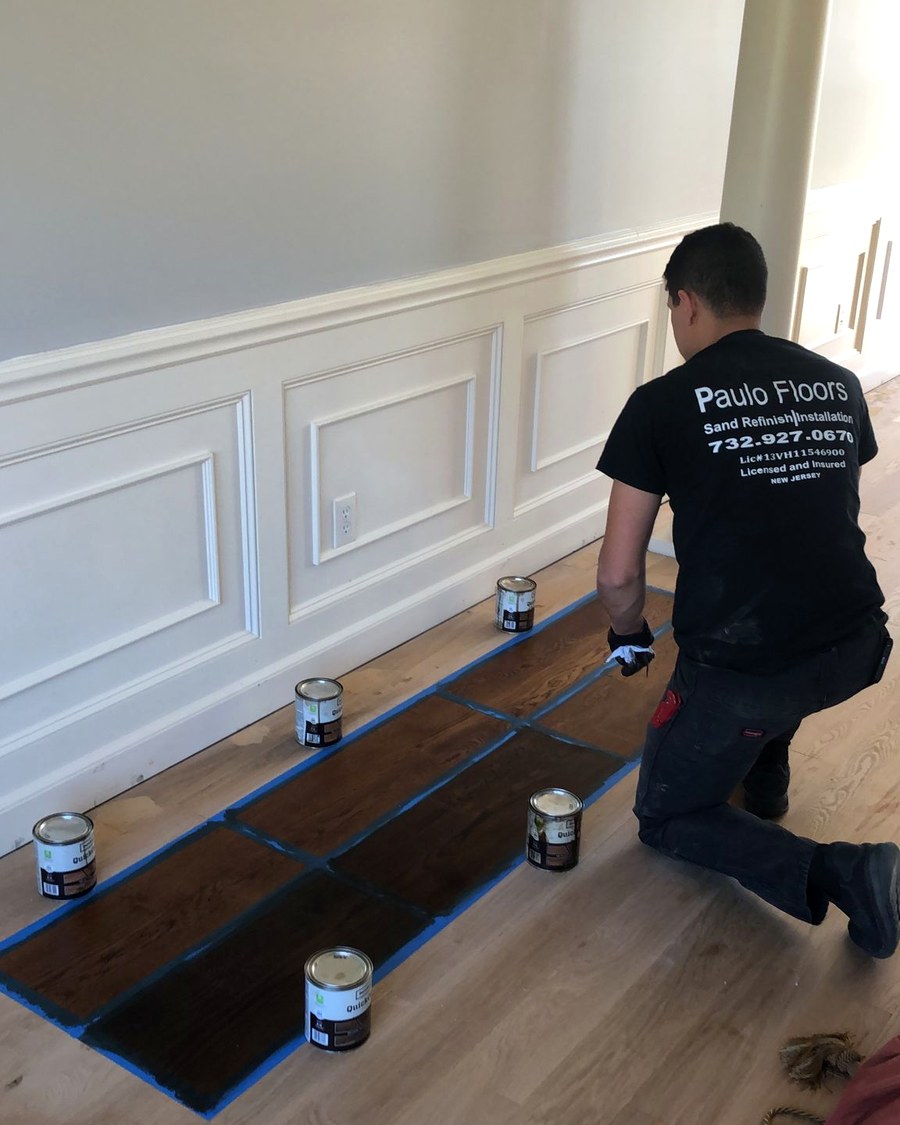 Testing stain color options directly on the floor before committing to a final finish.