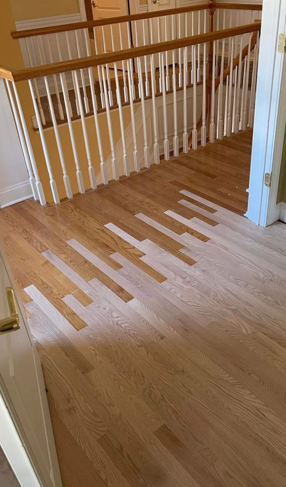 A herringbone medallion accent blending into wide-plank hardwood flooring near a staircase.