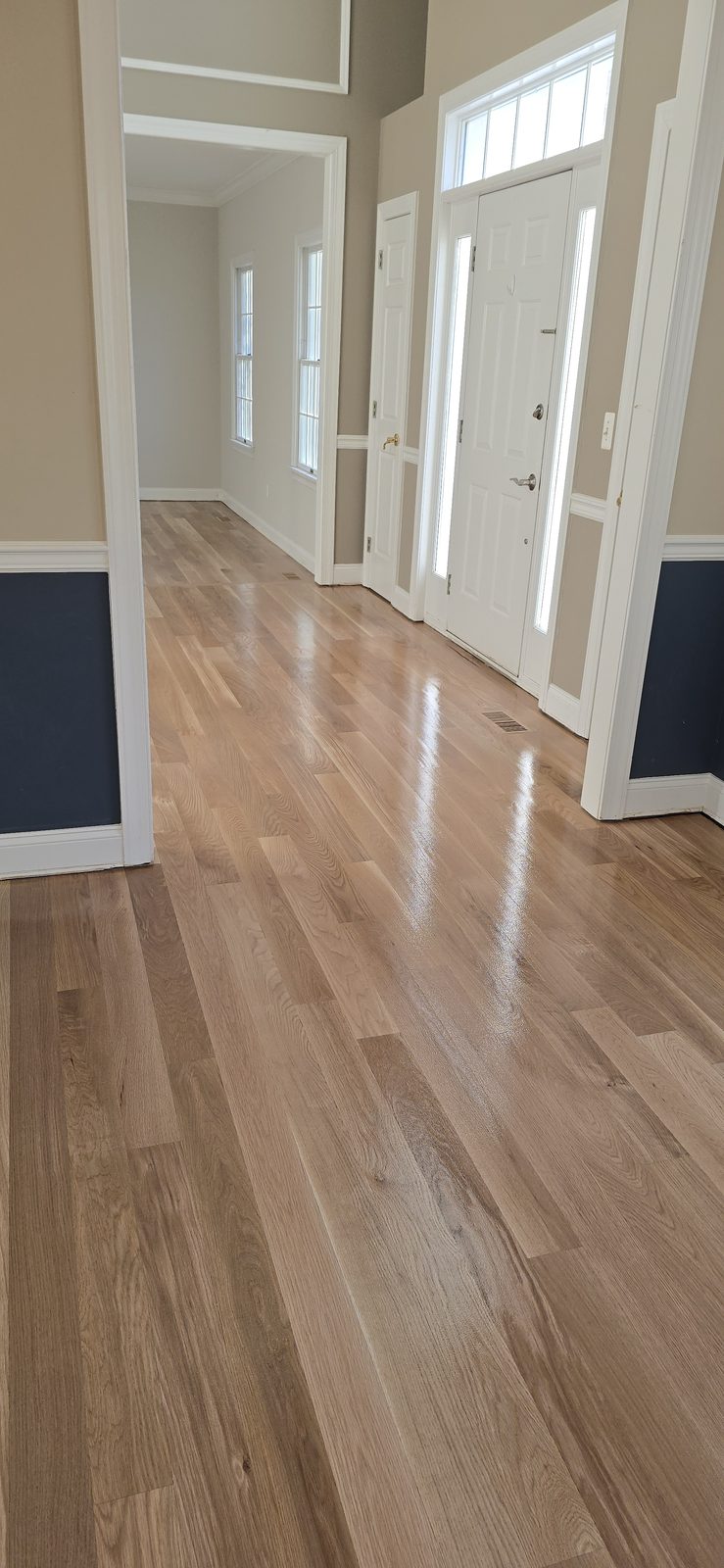 A glossy, freshly finished hardwood hallway leading to the front entry.
