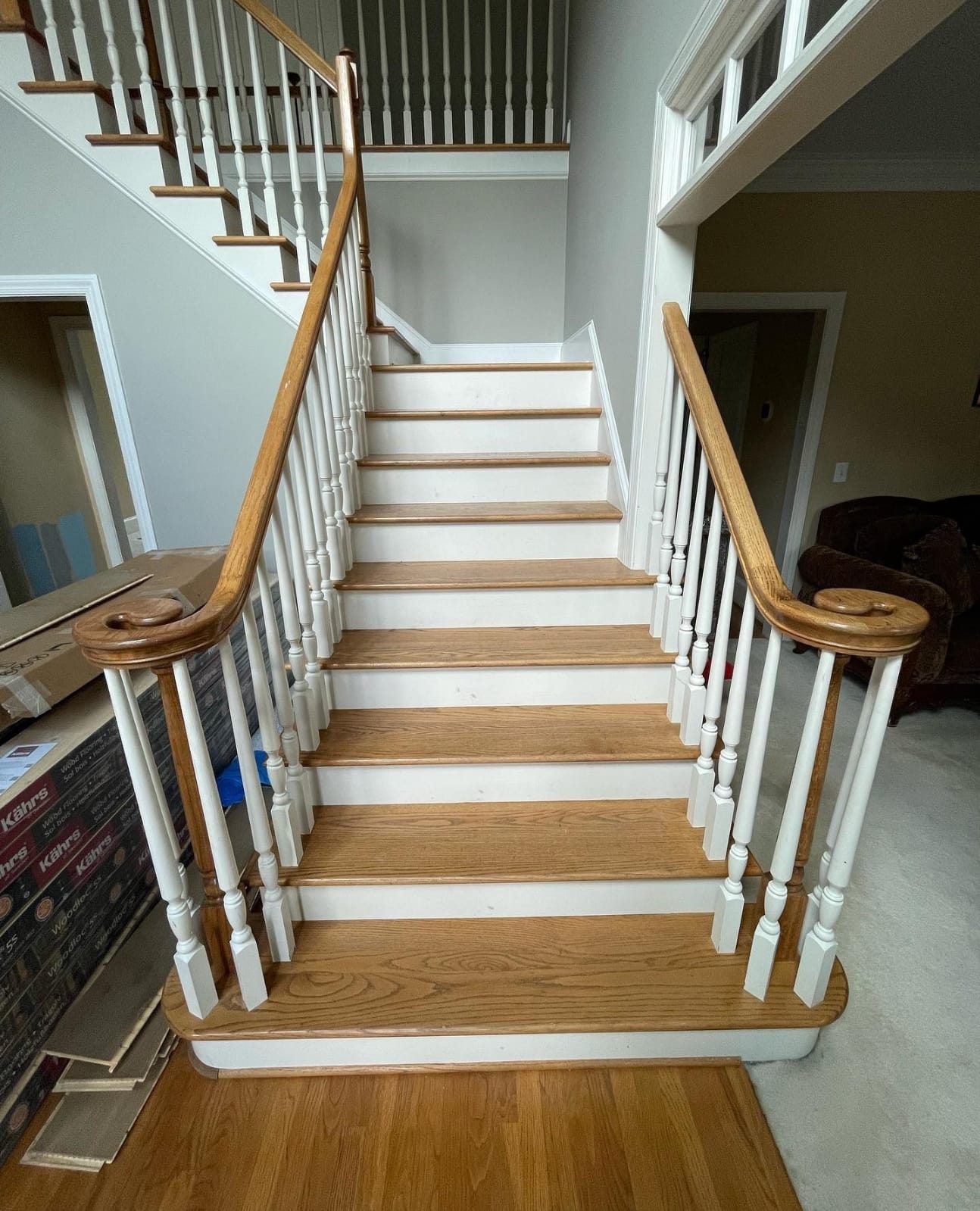 A straight-run staircase with warm oak treads and white risers, flooring materials staged nearby.