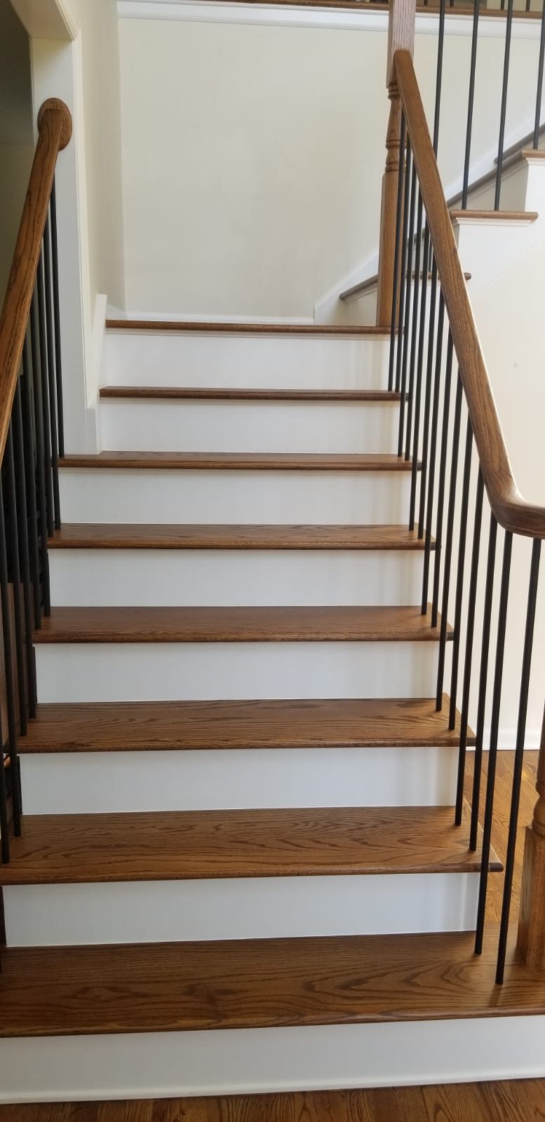 A staircase finished with dark stained treads and black iron balusters.