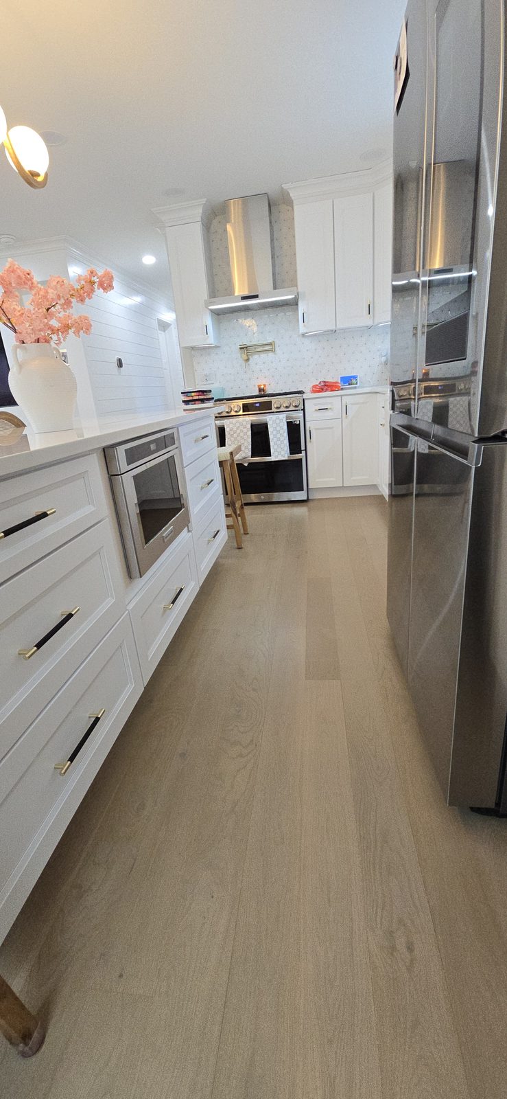 A kitchen with wide-plank hardwood flooring and stainless steel appliances.