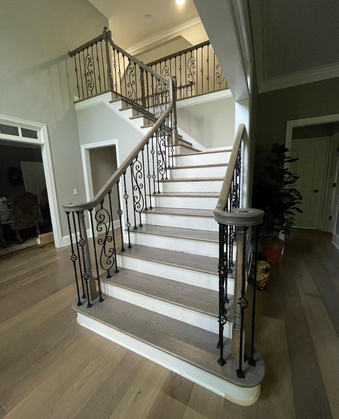Ornate wrought iron stair balusters paired with gray-stained wood treads.