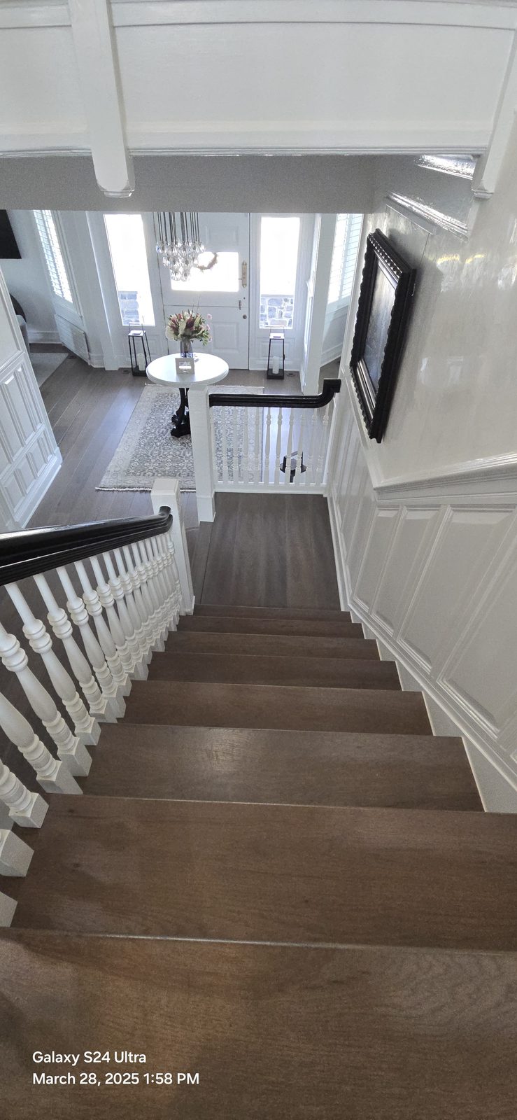 A staircase view down toward an entryway with a round table and fresh flowers.
