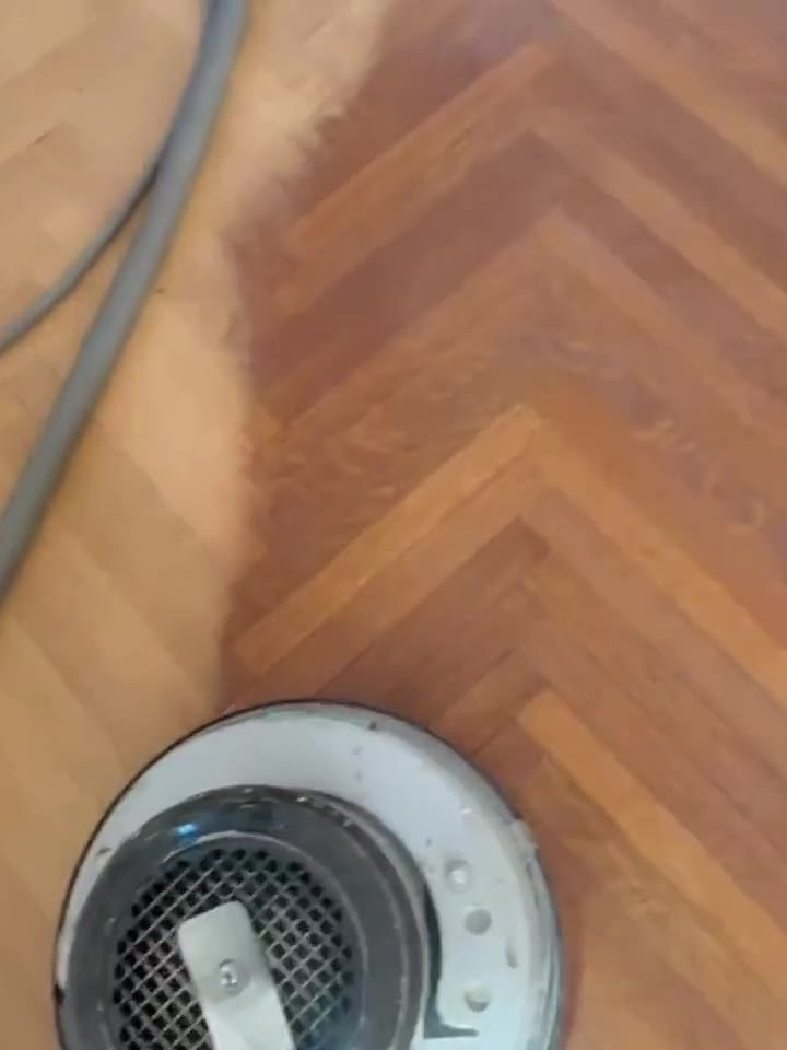 An edge sander finishing the perimeter of a herringbone floor.