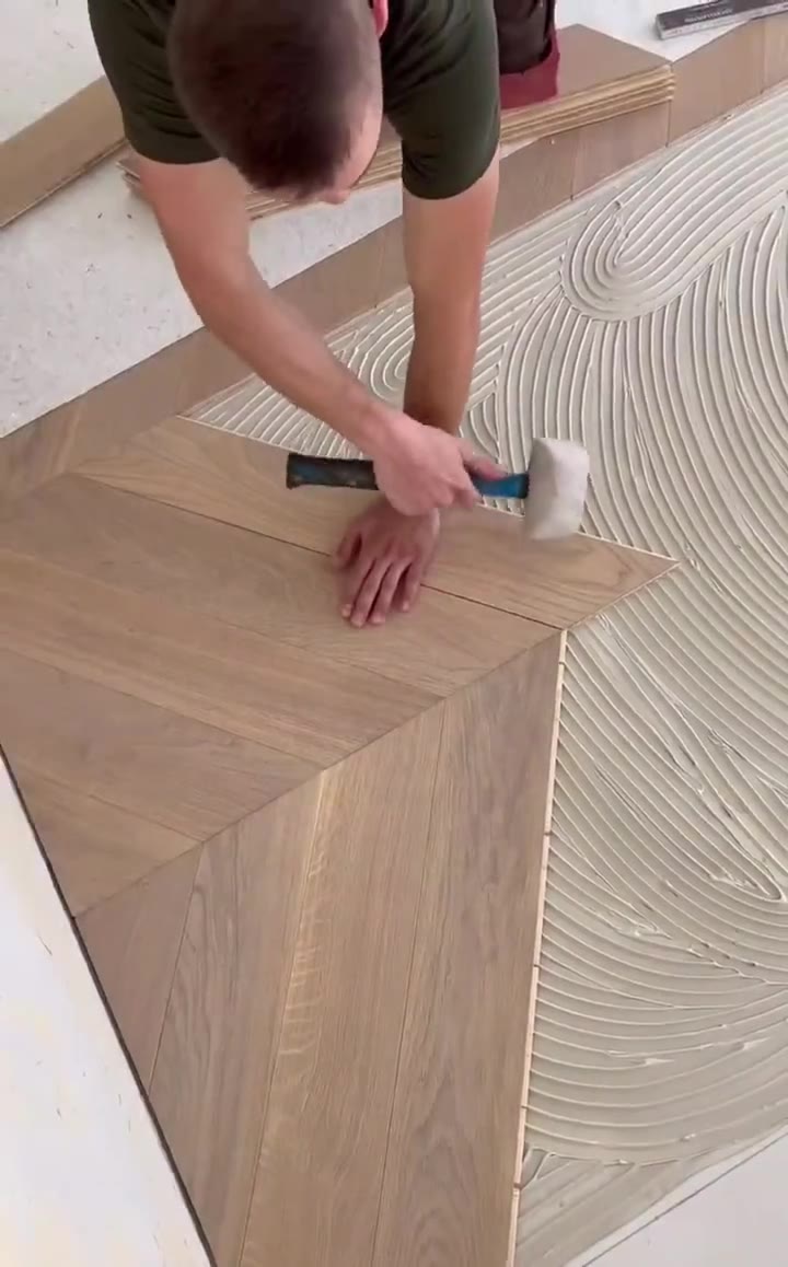 Trimming a herringbone hardwood point into place with a rubber mallet.