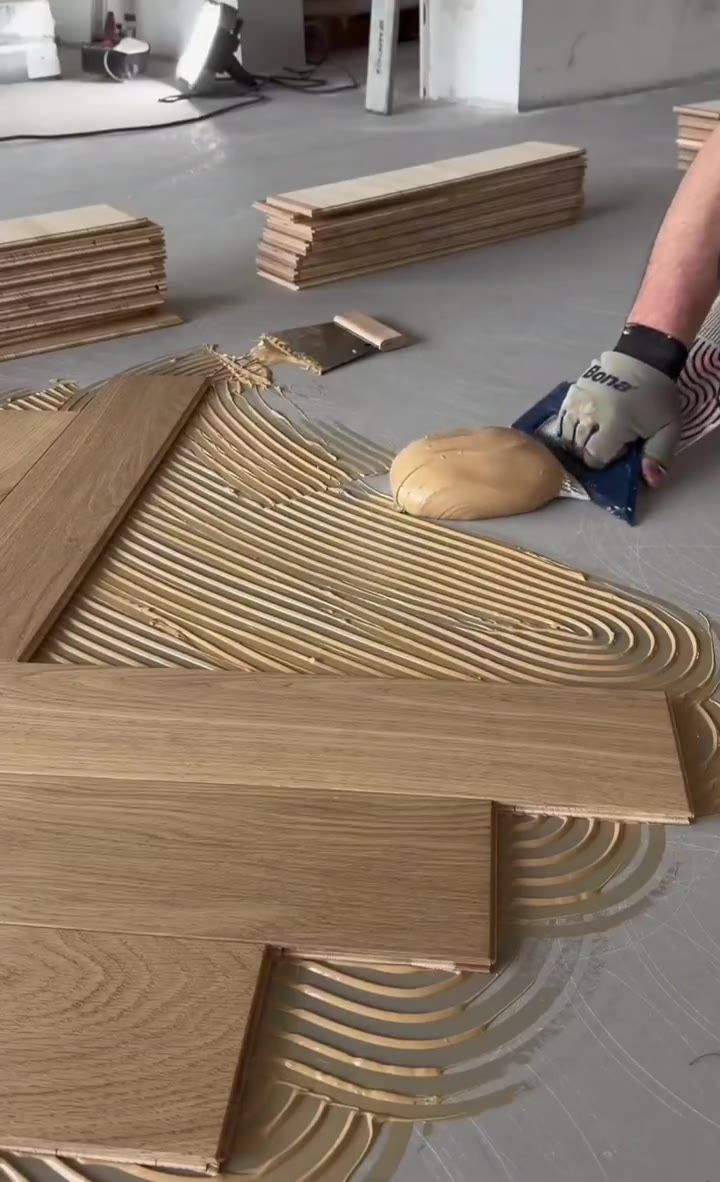 Prepping adhesive and staging planks for a herringbone floor installation.